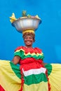 Vertical footage of a Palenquera holding bowl of fruits above head, dressed with colorful clothes