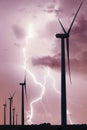 Vertical format of silhouette of wind turbines on a farm in Iowa on stormy sky with lightning strike background. Royalty Free Stock Photo