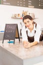 Vertical frame of beautiful caucasian barista woman happy with placing hands-on table of coffee bar near takeaway sign