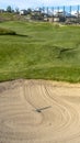 Vertical frame Bunker and fairway of a golf course with homes mountain and sky background