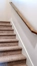 Vertical frame Carpeted indoor staircase of home with brown handrail against white side wall Royalty Free Stock Photo