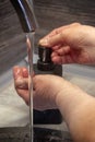 The vertical frame. An elderly woman washes her hands. in the frame - hands, a tap with running water and soap