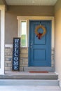 Vertical frame Golden wreath on the blue front door of a house with concrete and stone wall Royalty Free Stock Photo