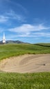 Vertical frame Golf course with sand bunker and vibrant fairway under blue sky on a sunny day Royalty Free Stock Photo