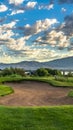 Vertical frame Hole filled with sand amid a grassy terrain against home lake mountain and sky Royalty Free Stock Photo