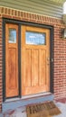 Vertical frame Home with brick and wood wall sections and glass paned front door and sidelight