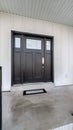 Vertical frame Home entrance with front porch and black front door against white panelled wall Royalty Free Stock Photo