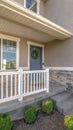 Vertical frame Home facade with small porch and blue gray front door with green leafy wreath