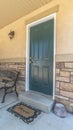 Vertical frame Home with green door yard windows and porch bench against stone brick wall Royalty Free Stock Photo