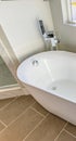 Vertical frame Interior of a bathroom with a smooth and glossy bathtub in th corner