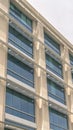 Vertical frame Modern building facade close up with glass windows and sunlit concrete wall Royalty Free Stock Photo