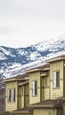 Vertical frame Row of cream colored homes with snow covered mountain and cloudy sky background Royalty Free Stock Photo