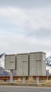 Vertical frame Selective focus mailboxes beside a road against snowy mountain and cloudy sky