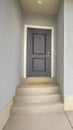 Vertical Front view of a home with gray front door and wood shutters on the window