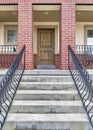 Vertical Front view of home with stairs going up to the elevated porch and brown door Royalty Free Stock Photo