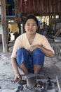 Burmese woman wearing traditional tanaka makeup with her tools making metal knives