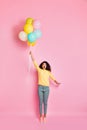 Vertical full length photo of astonished emotional funny teenager hipster holding many baloons in hand feeling she can