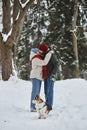 Romantic young couple kissing in winter forest and walking cute dog Royalty Free Stock Photo