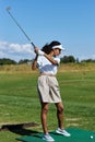 Vertical woman playing golf on green grass and swinging golf club Royalty Free Stock Photo