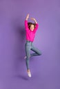 Vertical full size photo of cute cheerful nice little girl jump up air raise hands ballet isolated on violet color Royalty Free Stock Photo