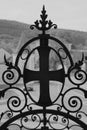 Vertical grayscale closeup of a decorative metal cross on the gate against the blurry background. Royalty Free Stock Photo