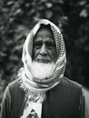 Vertical grayscale of an old poor Muslim male with an headscarf on the blurred background