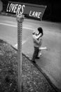 Vertical grayscale shot of the couple embracing beneath a street sign at Lovers Lane.