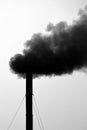 Vertical grayscale shot of a factory emitting black toxic smoke