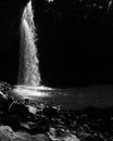 Vertical grayscale shot of a flowing splashing waterfall in aforest