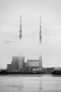 Vertical grayscale shot of industrial towers in misty weather Royalty Free Stock Photo