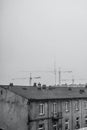 Vertical grayscale shot of an old building roof on tower cranes background