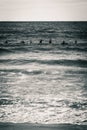 Vertical grayscale shot of a sea with silhouettes of people