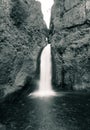 Vertical grayscale shot of a strong waterfall flowing in the river