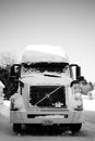 Vertical grayscale shot of a Volvo truck covered in snow on the roadside