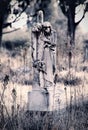 Vertical grayscale of a statue of a grieving woman hugging the cross on the grave Royalty Free Stock Photo