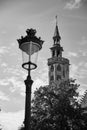 Vertical grayscale of a street lamp in front of Poortersloge against a cloudy sky, Bruges, Belgium
