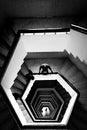 Vertical grayscale top view of a person looking down a geometric stairwell