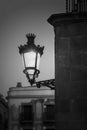 Vertical greyscale shot of a beautiful medieval lamp hanged on a stone building