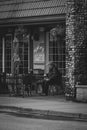 Vertical greyscale shot of an elderly male sitting in an outdoor bagel shop