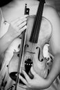 Vertical greyscale shot of a female holding a violin in her arms