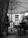 Vertical greyscale shot of a house backyard with chairs and table under an umbrella