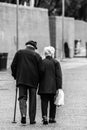 Vertical greyscale shot of an old romantic couple walking holding hands