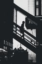Vertical greyscale shot of a silhouette of a person going down the iron stairs
