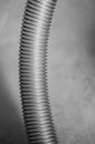 Vertical greyscale shot of the spiral tube of a vacuum cleaner