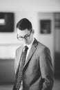 Vertical greyscale shot of a white male wearing a suit and tie attire standing in a room Royalty Free Stock Photo