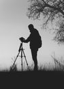 Vertical greyscale of the silhouette of a cameraman surrounded by trees at daytime Royalty Free Stock Photo