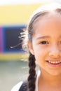 Vertical half face portrait of smiling cauasian elementary schoolgirl in schoolyard, copy space