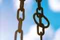 Vertical hanging rusty chain. Sunlight, blue background. For text area