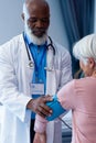 Vertical of happy diverse senior male doctor taking blood pressure of female patient, copy space Royalty Free Stock Photo