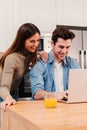 Vertical. Happy young couple using a laptop to watch at notebook screen browsing internet enjoying leisure time at home Royalty Free Stock Photo